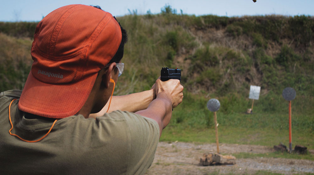 man in brown t-shirt and ref knit cap | How Should You Hold a Handgun for Maximum Accuracy | Featured