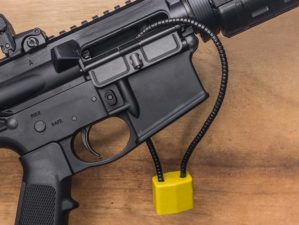 AR-15 semi-auto assault rifle gun on a wooden background unloaded and with a secure child lock going through the chamber | How to Use a Gun Lock | Featured