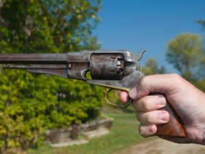 A hand holding an antique revolver in a shooting position | Weirdest Guns | 6 of the Weirdest Guns Ever Made | Featured