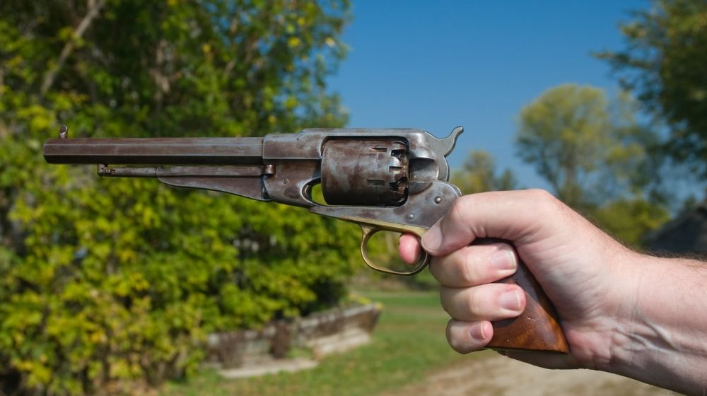 A hand holding an antique revolver in a shooting position | Weirdest Guns | 6 of the Weirdest Guns Ever Made | Featured
