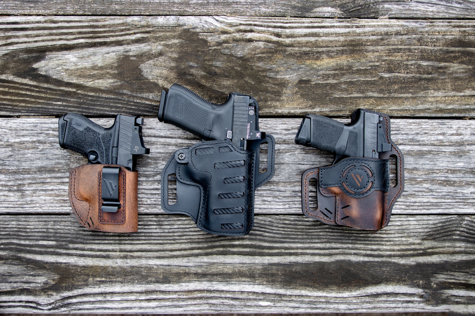 best handguns under $500 a couple of holsters sitting on top of a wooden table